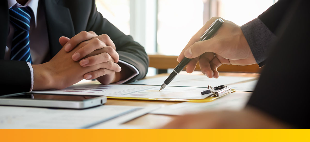 man holding pen to paperwork in a meeting